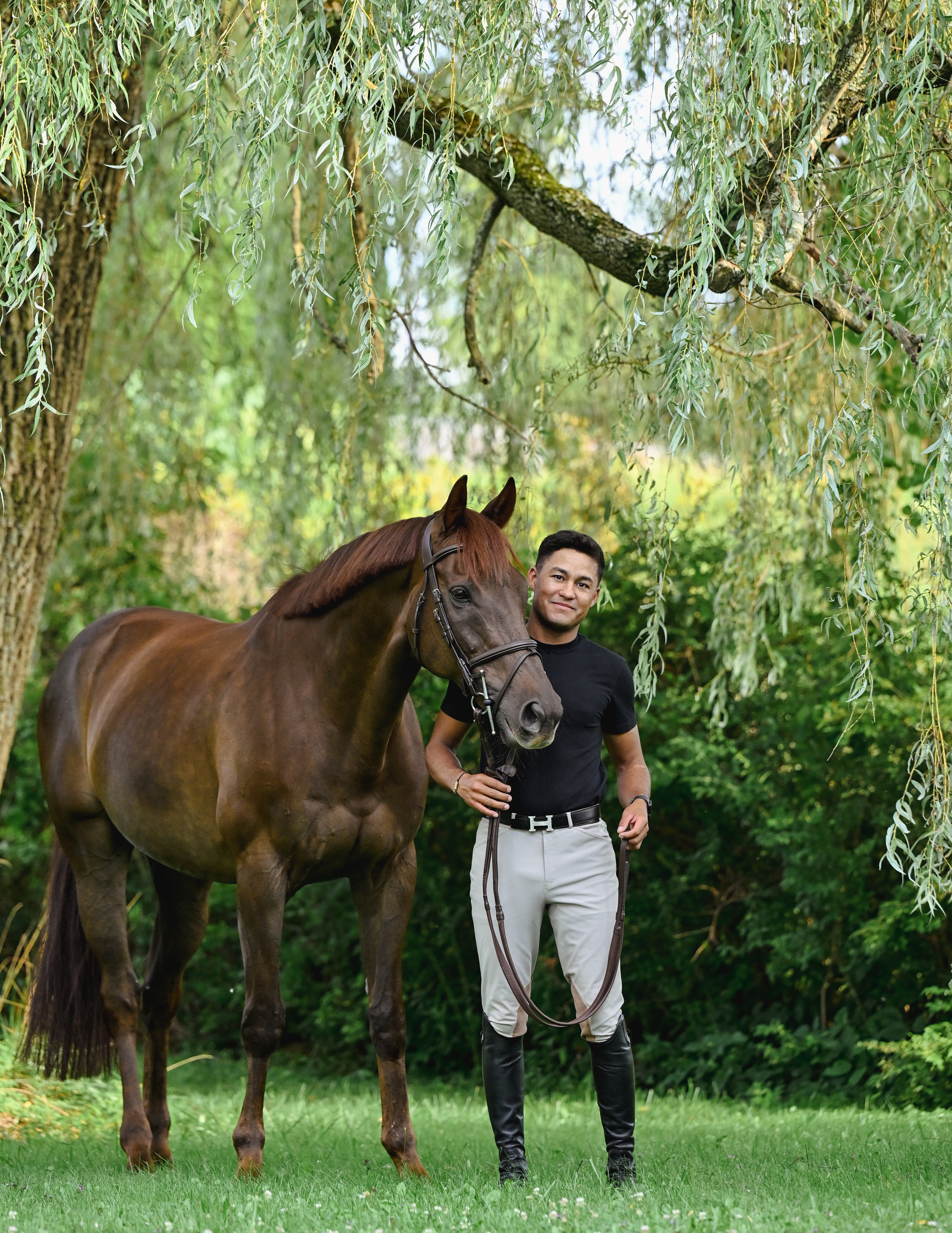 Michel Feitosa with horse under a willow tree